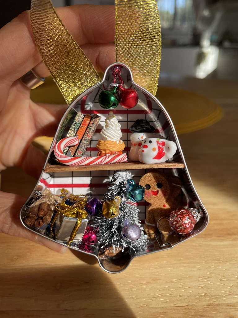 Handmade miniature scene inside a bell-shaped tin